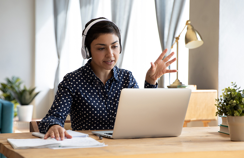 Woman wearing headphones and using a laptop