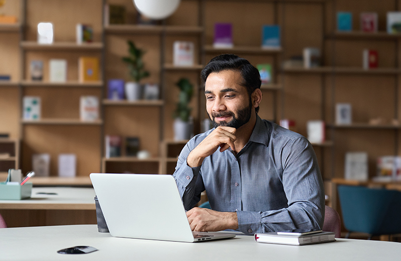 Man sitting at a desk while working on a laptop