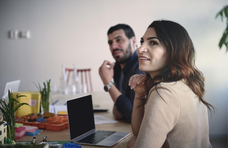 A man and a woman sitting in front of a laptop