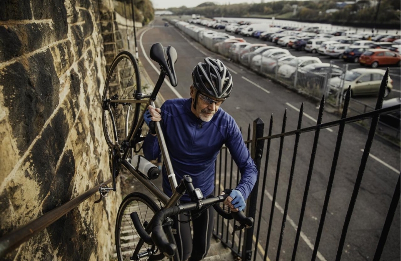 Retired man walks bike up stairs